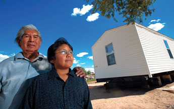 Lebeck Ukestine and grandson Joel Gchachi, 10, stand in front of a new mobile home donated with the help of people in the Zuni community and the Zuni Housing Authority. By sheer serendipity, Gchachi saved his sleeping grandfather as fire swept through their home. Gchachi had set out walking to school and came back home to ask his grandfather for a ride. All their belongings and family mementos were turned to ash. "The only thing they carried from the fire was what was the clothes on their backs," Zuni Housing Authority Director Michael Chavez said. © 2011 Gallup Independent / Adron Gardner 